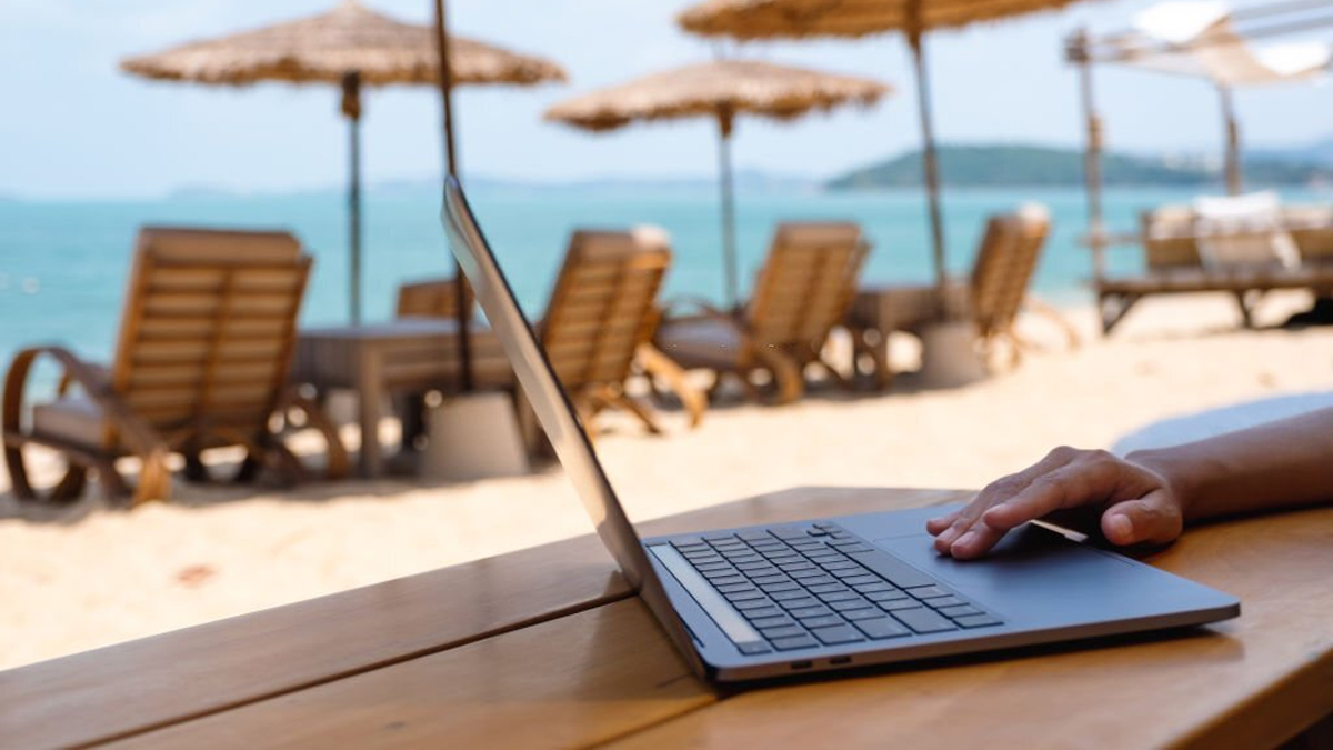 Woman working on laptop on the beach