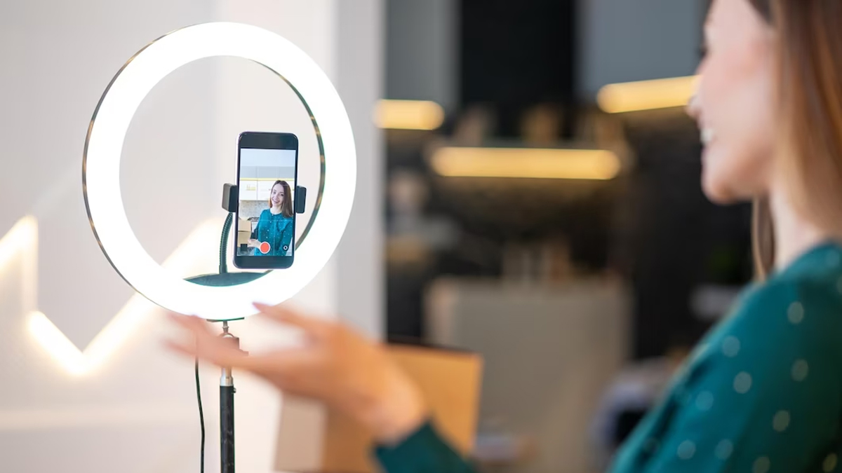 Young smiling woman records video by cellphone