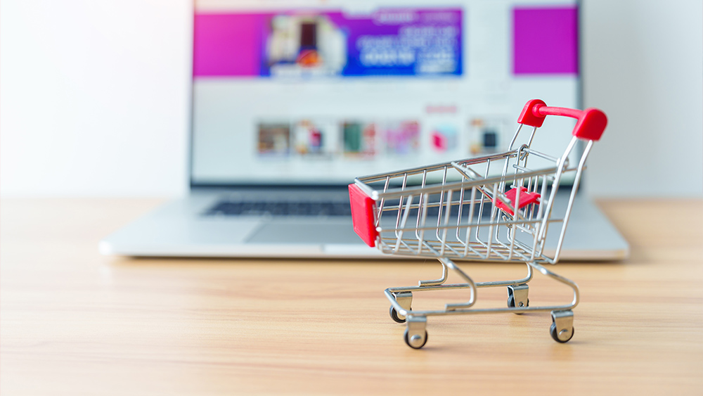 Shopping cart and a laptop showing online shop