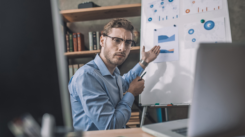 Young bearded man in eyeglasses holding webinar