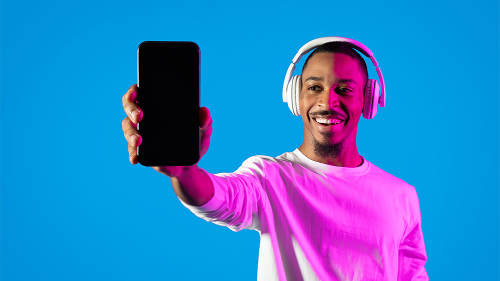 Cheerful young man showing a smartphone