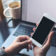 Business woman holding mobile phone with blank display