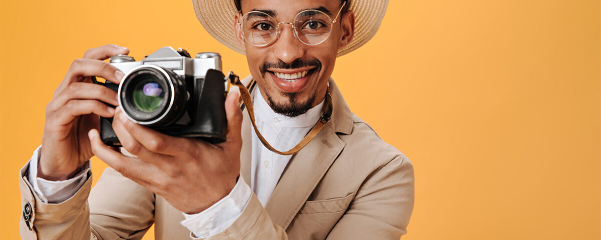 Man in beige hat is holding retro camera