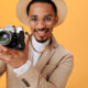 Man in beige hat is holding retro camera