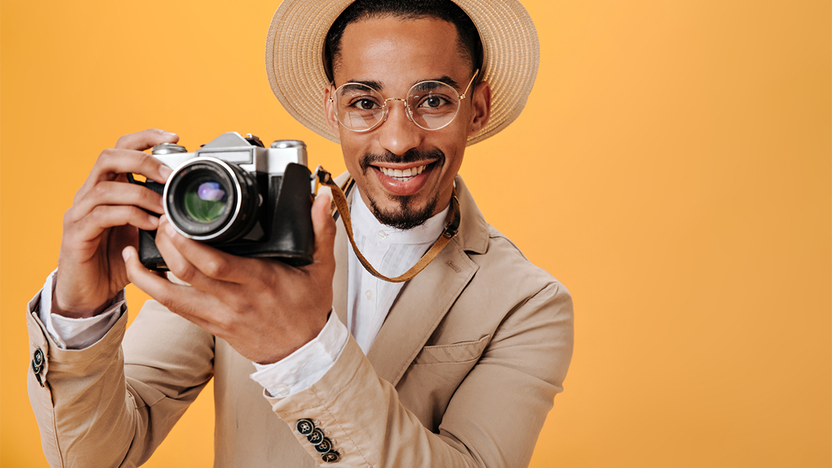 Man in beige hat is holding retro camera