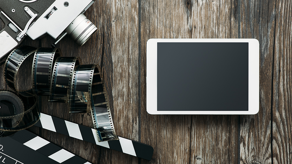 Film production concept with tablet and old camera with films on the table