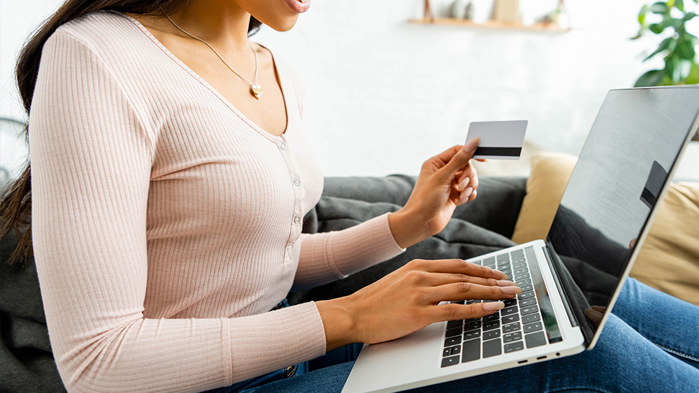 Woman in front of laptop doing online payment with a bank card