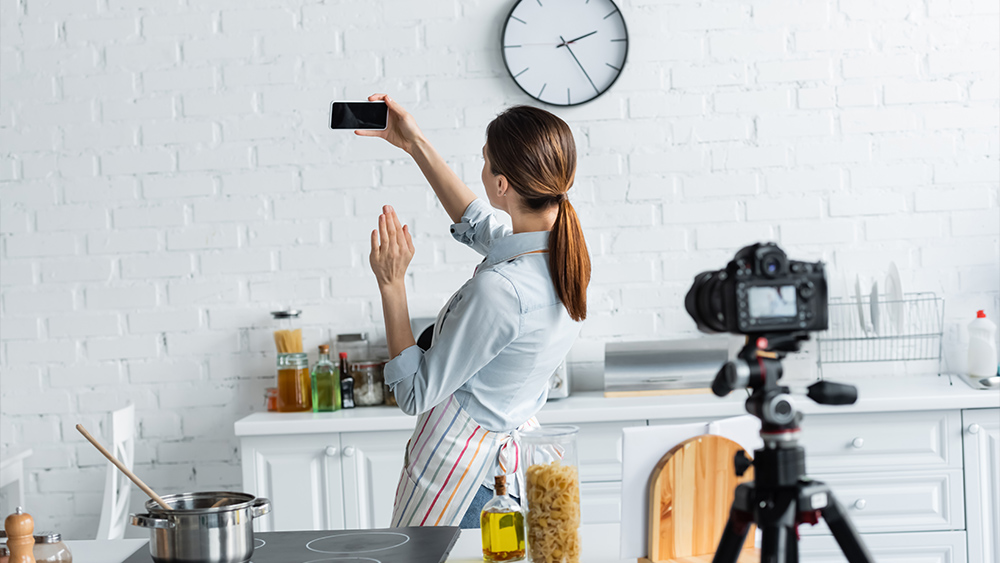 Young culinary blogger waving hand near smartphone